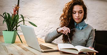 Student reading and using laptop to study